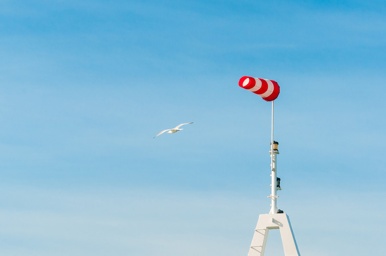 Horizontally flying windsock wind vane with blue sky in the background. Big birds seagulls flying around.