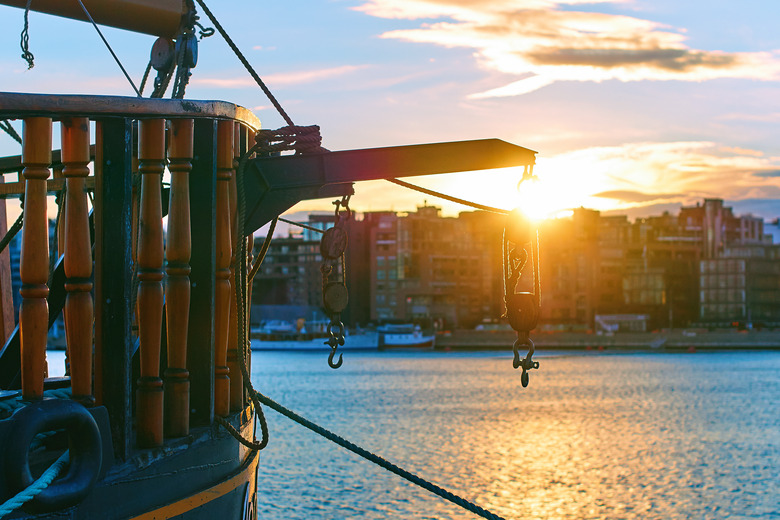 Winch with hooks on the stern of a wooden ship in the evening port with cityscape on background