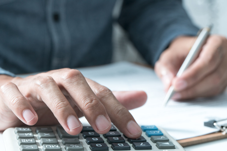 Man performing calculations with paper, pen and a calculator