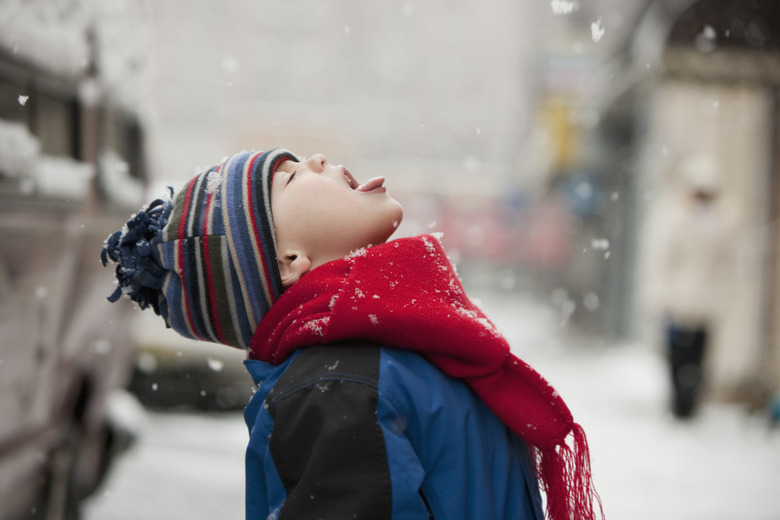 Caucasian boy catching snowflakes on tongue