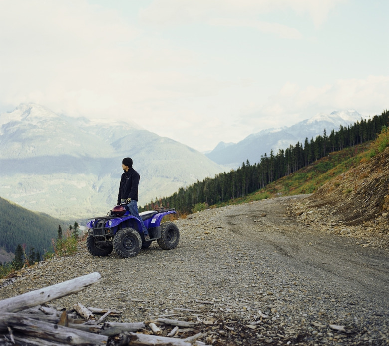 Man standing on ATV looking out at mountain view