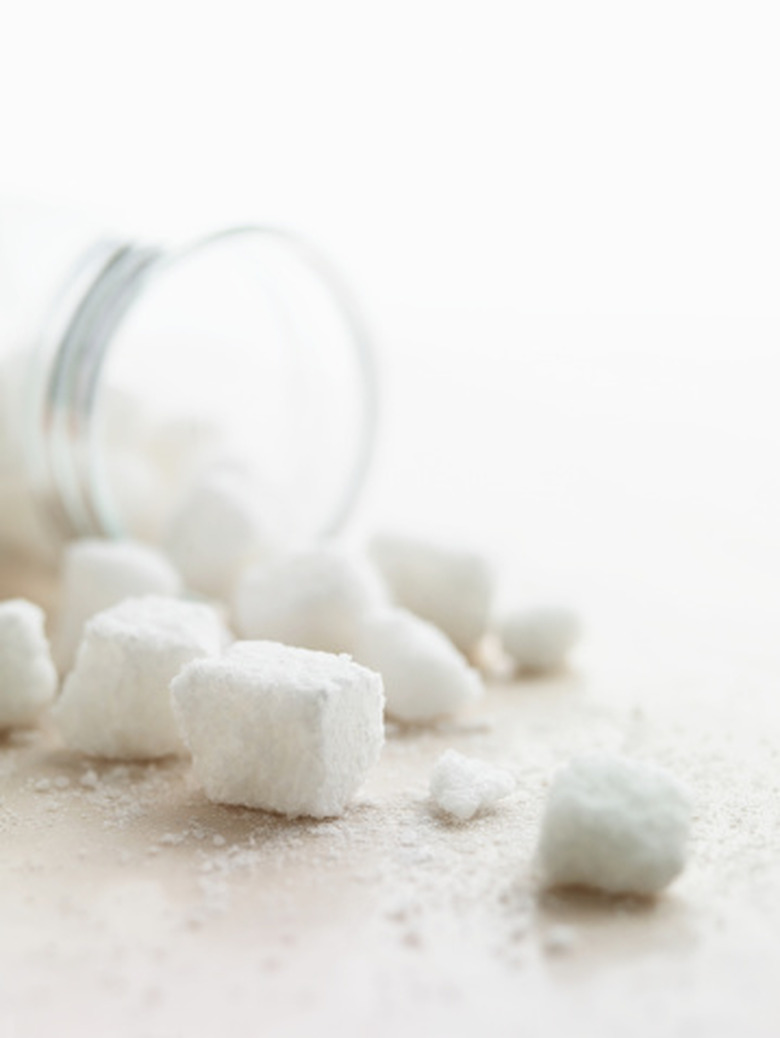 Cubes of sugar spilling out of a jar onto a table