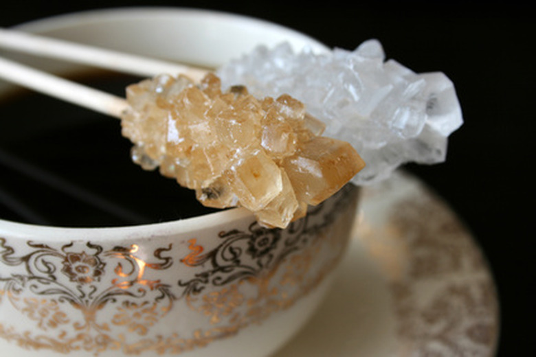 A stick of rock candy setting on top of a coffee cup to be used as a stirrer