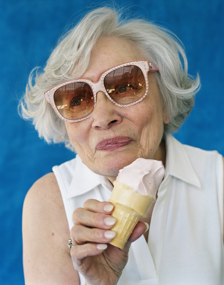 Senior woman wearing sunglasses, holding ice cream cone, close-up