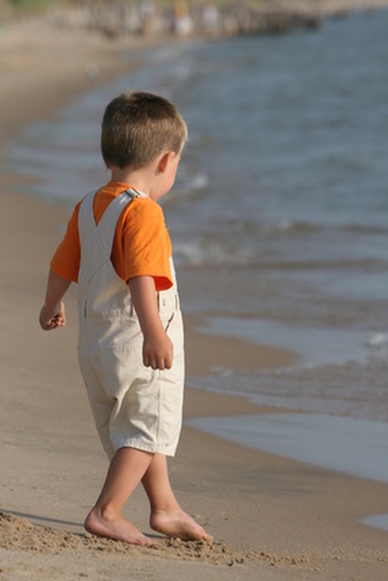 A young boy playing at the water's edge.