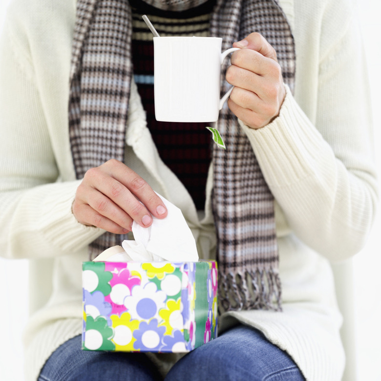 close-up of a woman holding a mug and a box of tissues