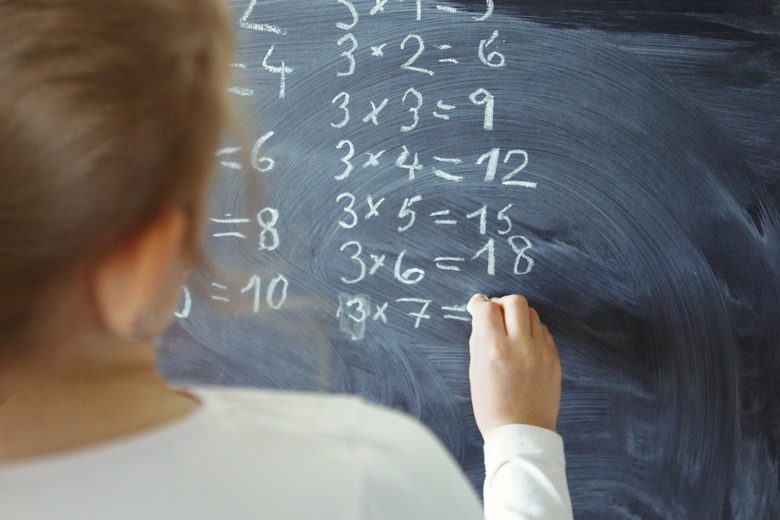 Young girl counting numbers on blackboard