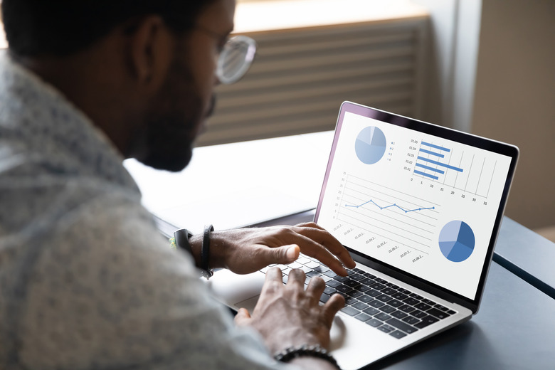 Focused young african ethnicity male marketing specialist analyzing graphs.