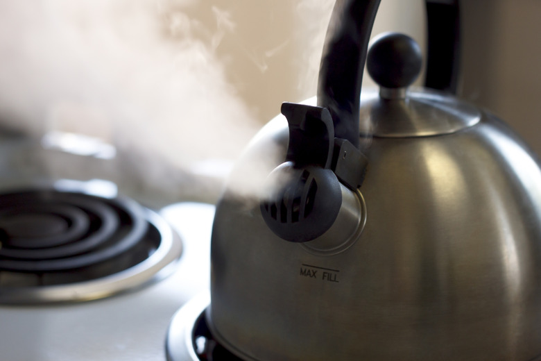 Water in a kettle turning into steam as it is heated.