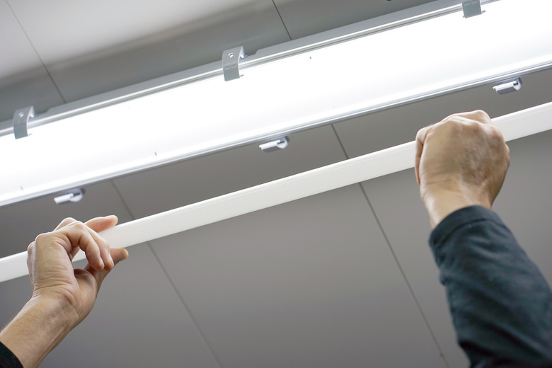 Electrician man worker installing fluorescent lamp