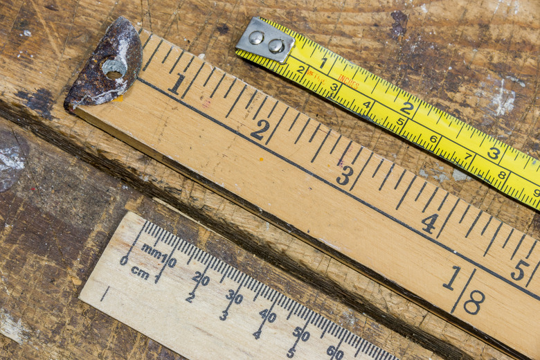 Old yard stick, ruler and tape measure on scratched workshop