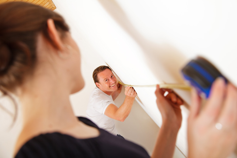 young couple measuring the rooms in their new apartment