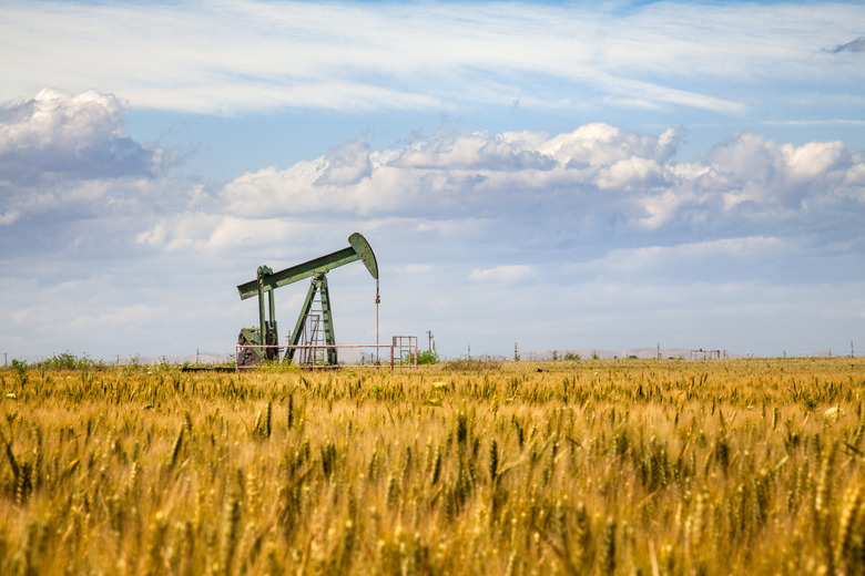 Lone Oil Pumpjack Amidst A Field of Golden Wheat