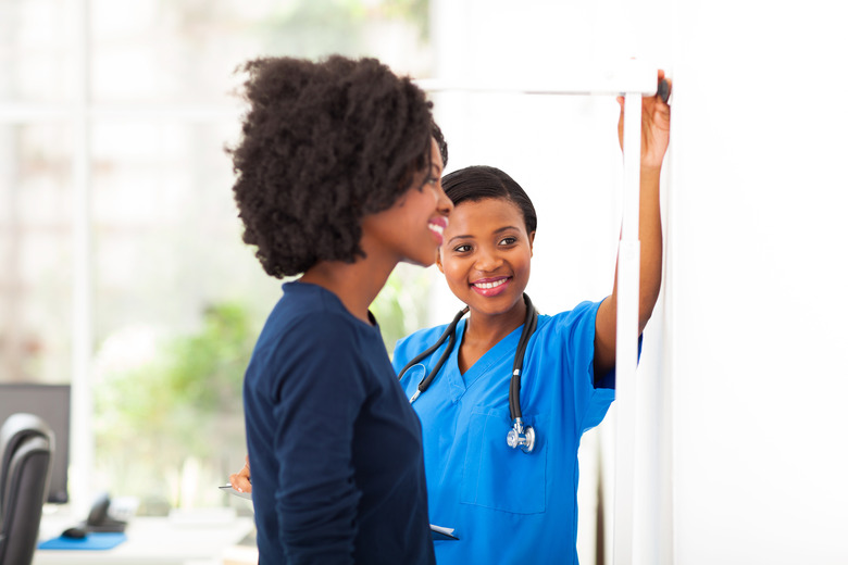 african nurse measuring patient's height