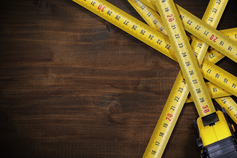 Tape Measures on Brown Wooden Background