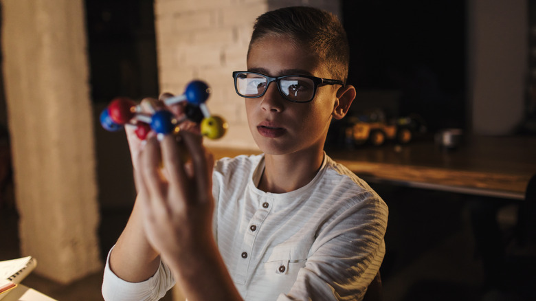 Schoolboy examining molecule model