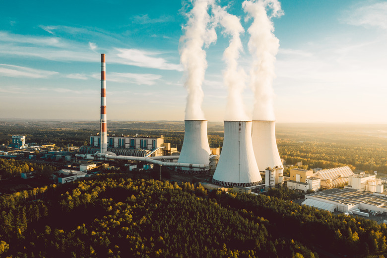 A Power plant with white smoke over it's chimneys