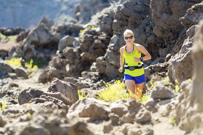 Young woman running in mountains on sunny summer day