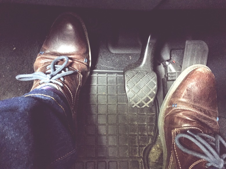 Low Section Of Man Wearing Shoes On Pedals In Car