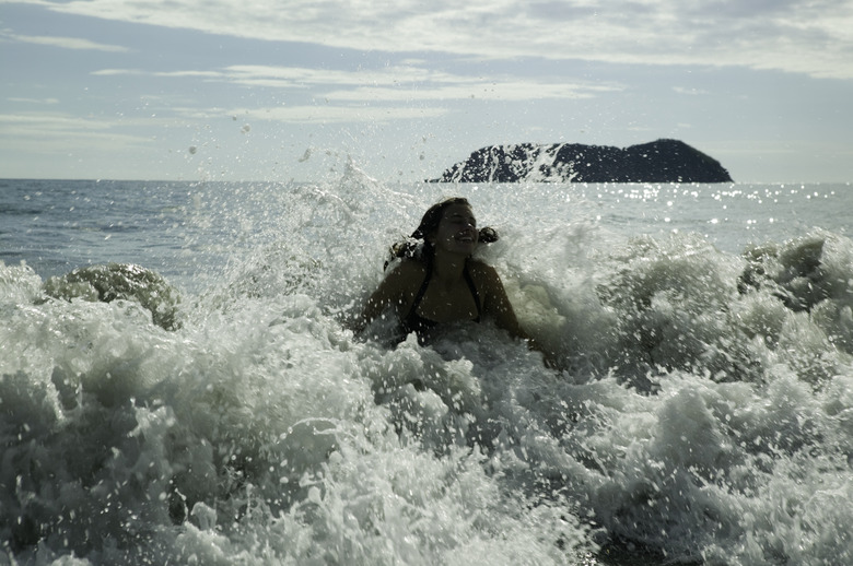 Teenage girl (14-15) swimming in sea amongst crashing waves