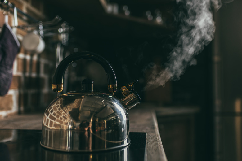 Close-up view of metallic kettle boiling on electric stove