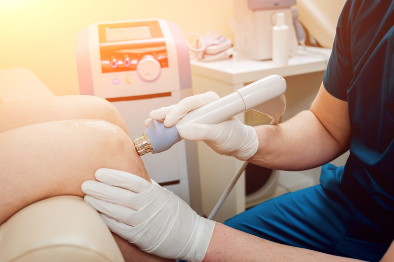 Medical device being used with electromagnetics for shock wave therapy. The magnetic field, rehabilitation. Physiotherapist doctor performs surgery on a patient's knee