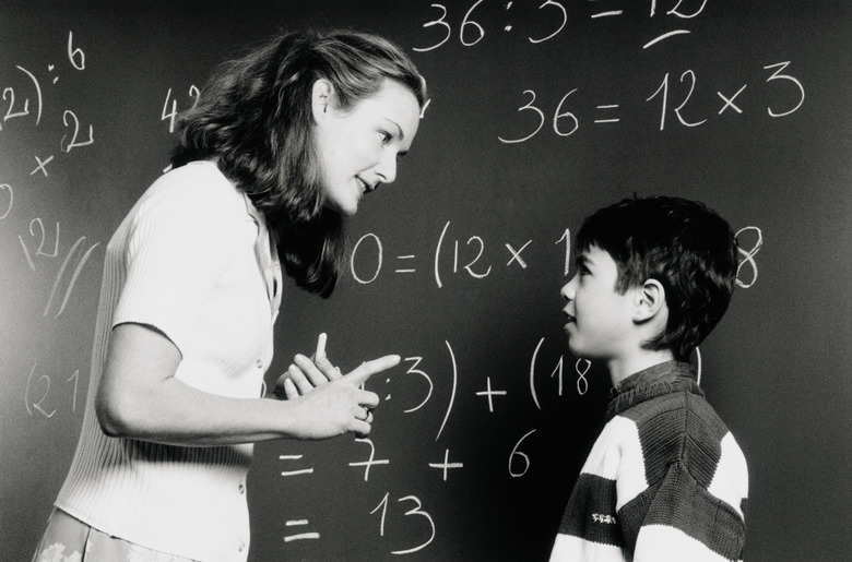 Teacher talking to student (6-8) by chalkboard (B&W)