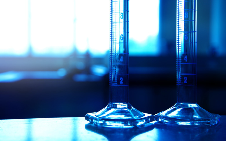 two glass measuring cylinders in chemical science technology laboratory background