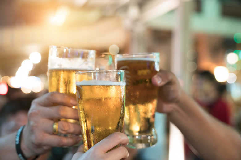 Friends toasting with glasses of light beer at the pub. Beautiful background of the Oktoberfest. A group of young people while relaxing at the bar. fine grain. Soft focus. Shallow DOF.