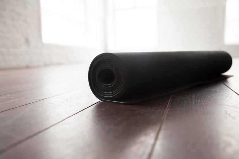 Rolled up yoga mat on natural wooden floor