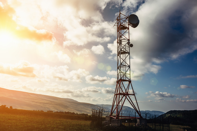 Telecommunication tower with dish and mobile antenna on mountains at sunset sky background