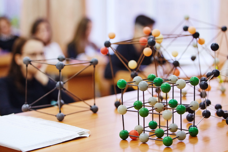 Students sit in the classroom and listen to a lecture in science. Plastic molecular educational model. Soft focus background image