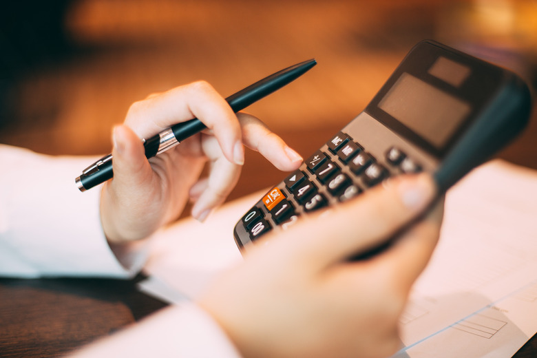 Close-up of hand holding pen and using calculator