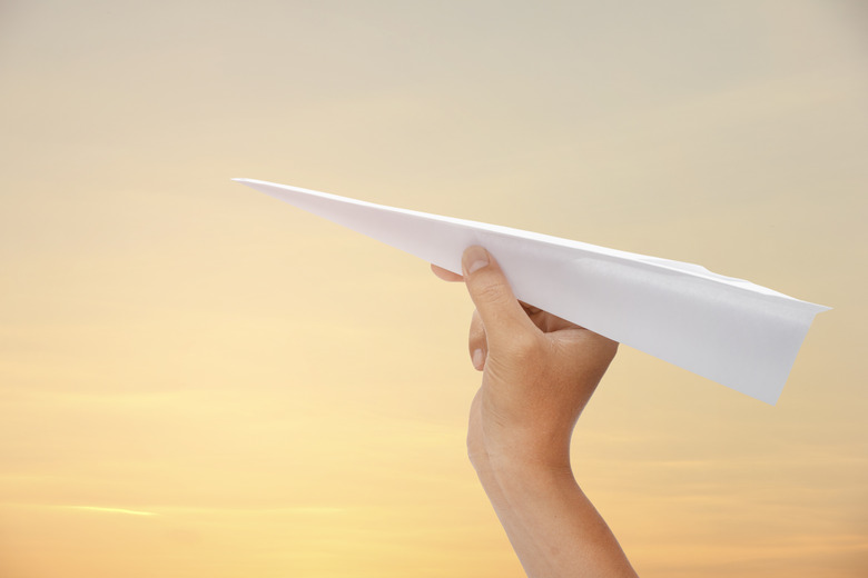 paper plane in hand on the sky background.