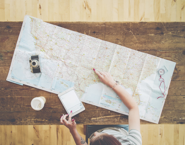 Caucasian woman planning trip with digital tablet and map on wooden table