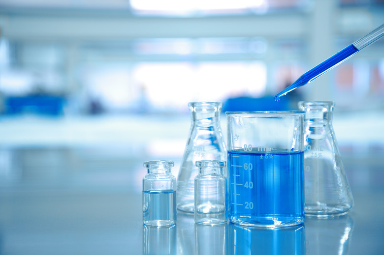 blue drop into glass beaker with flask and science laboratory