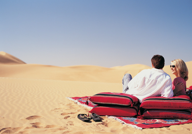 Rear View of a Couple Lying on a Blanket and Cushions Looking at the Desert View