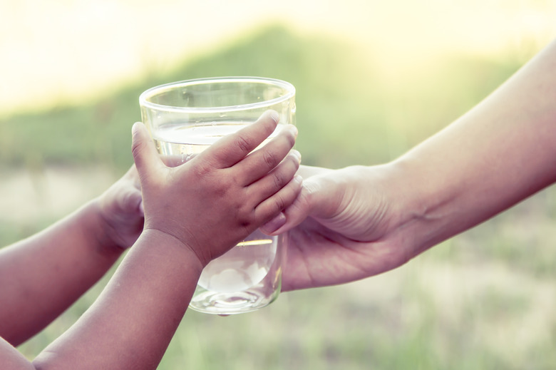 Woman hand giving glass of fresh water to child