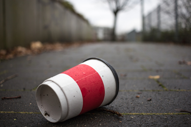 Used Coffee mug at sidwalk as symbol for pollution.