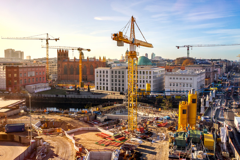 Cranes At Construction Site Against Buildings In City