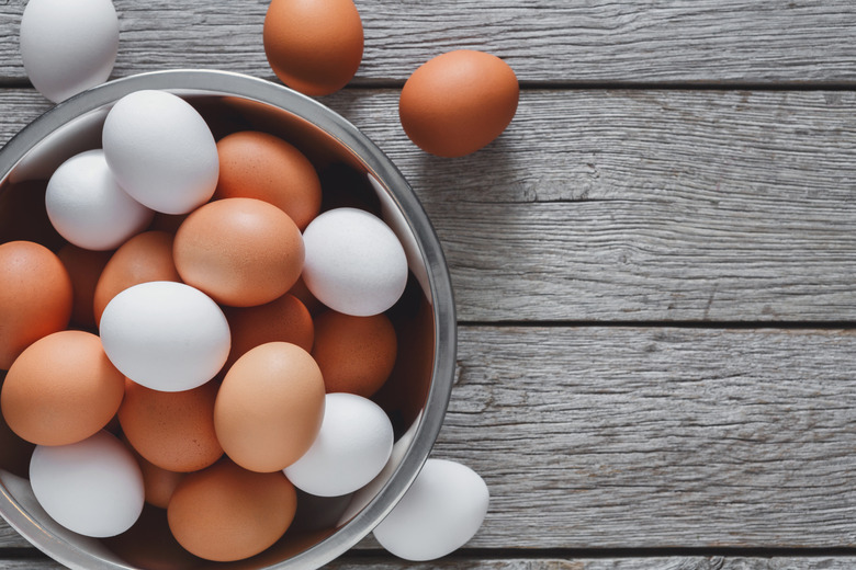 Fresh brown eggs in bowl on wood background