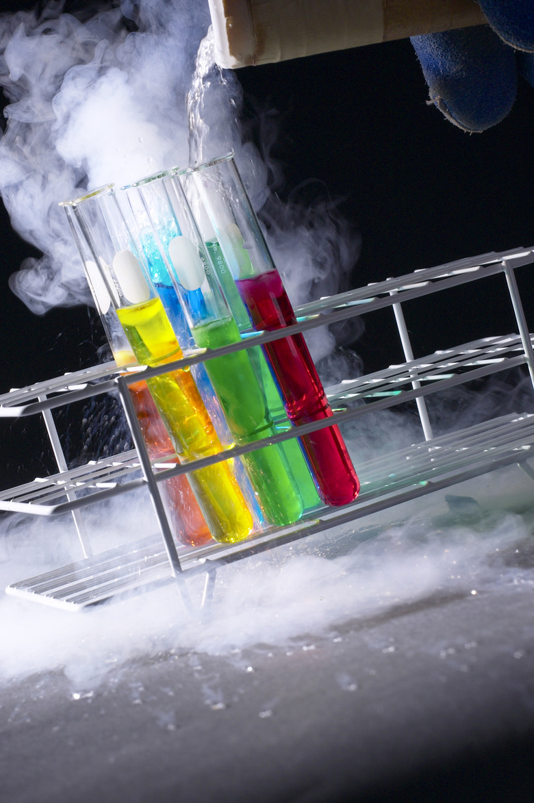 Fingers pouring chemicals into test tubes