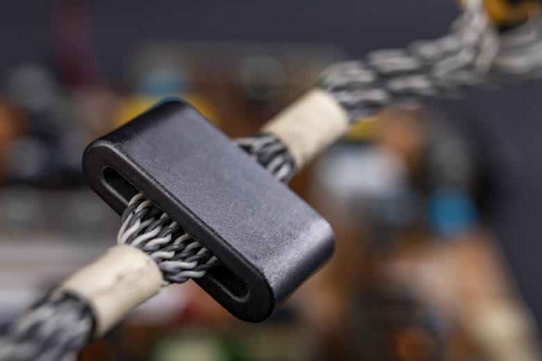 Magnet on several electric wires. Ferrite filter to protect the electrical device. Dark background.