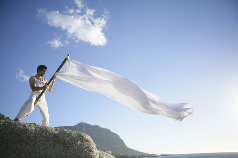 Young man standing on a rocky cliffy holding a white flag