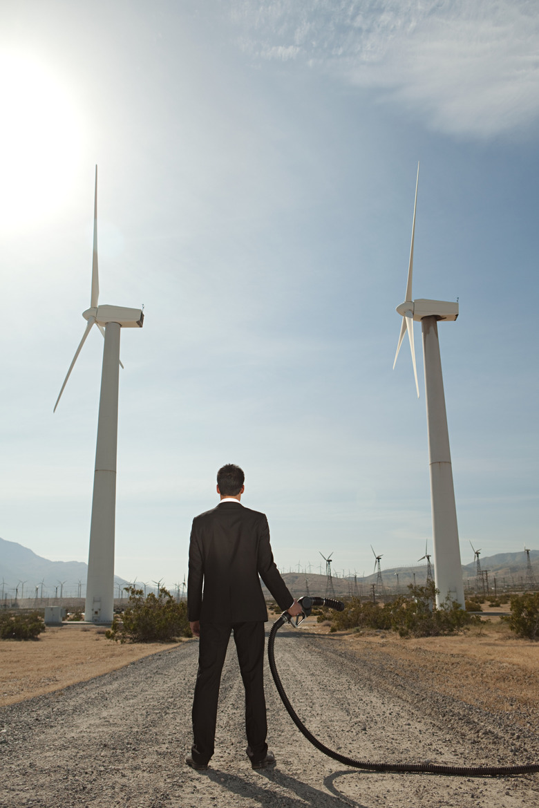 Businessman at wind farm with gas pump