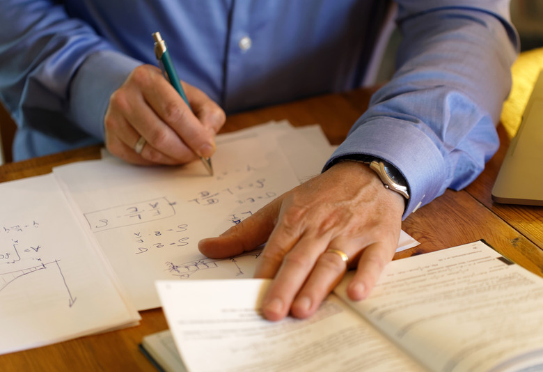 Hands of a businessman making calculations on a paper sheet