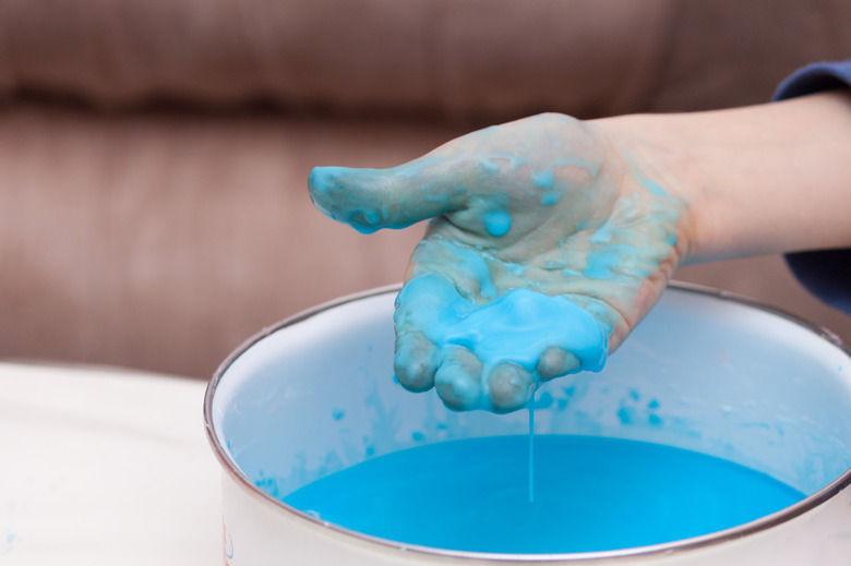 Closeup of kids hand holding substance, cornstarch and water mixture, doing a science experiment