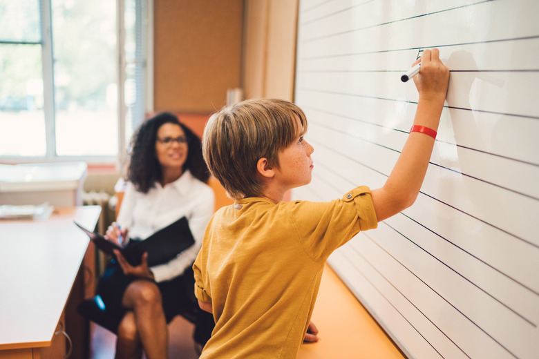 Schoolboy solving maths on whiteboard