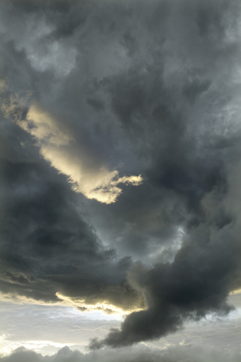 Looking up to stormy sky with black clouds forming a tornado.