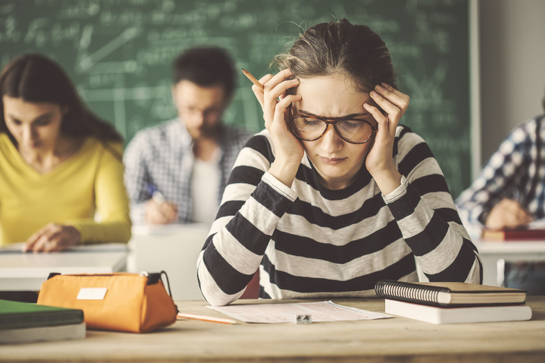 Students solving problem quiz in classroom behind blackboard